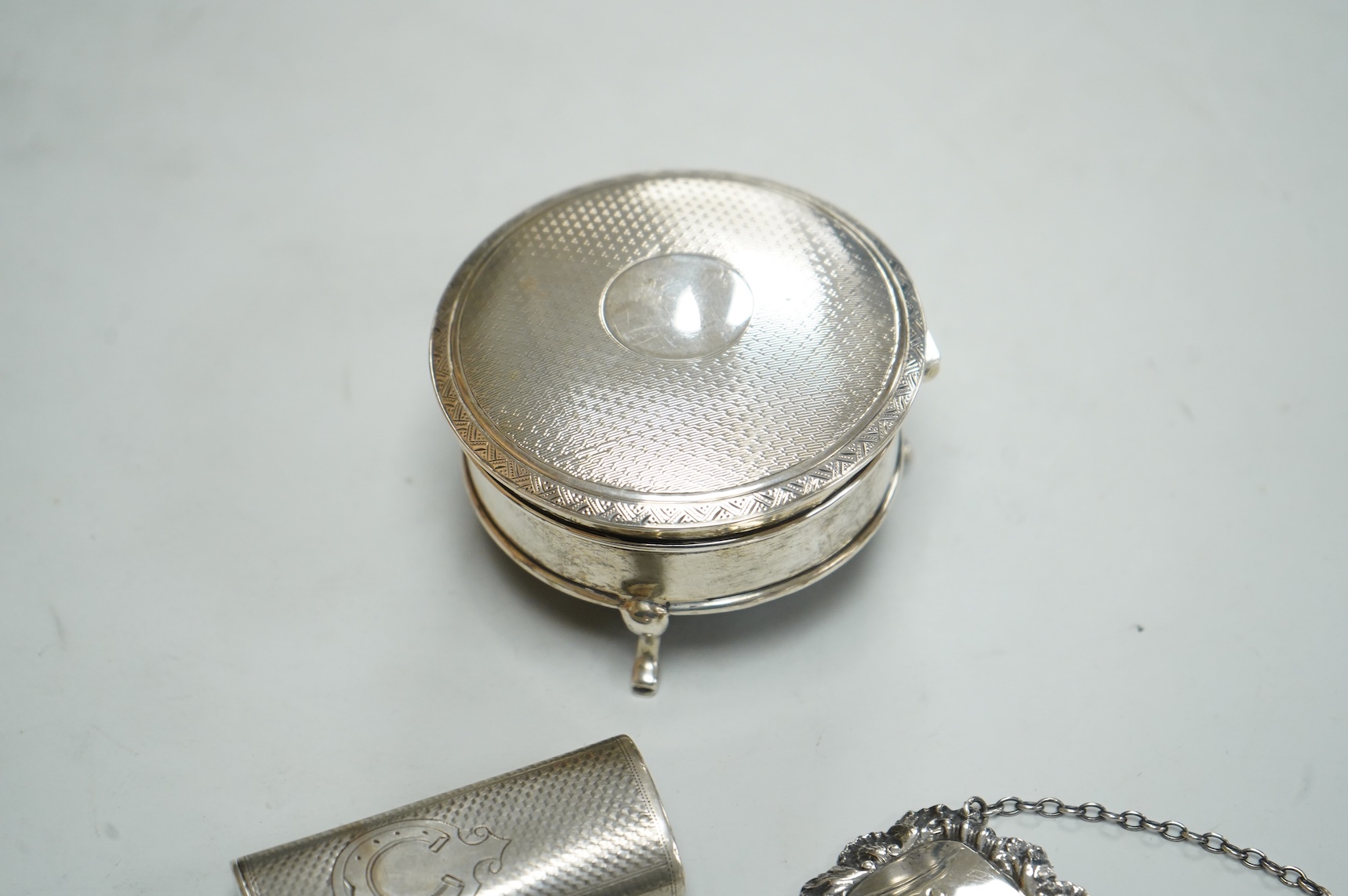 A George V silver mounted circular trinket box by Horton & Allday, Birmingham, 1916, diameter 75mm, together with a 19th century German? white metal vesta case and a modern silver wine label.